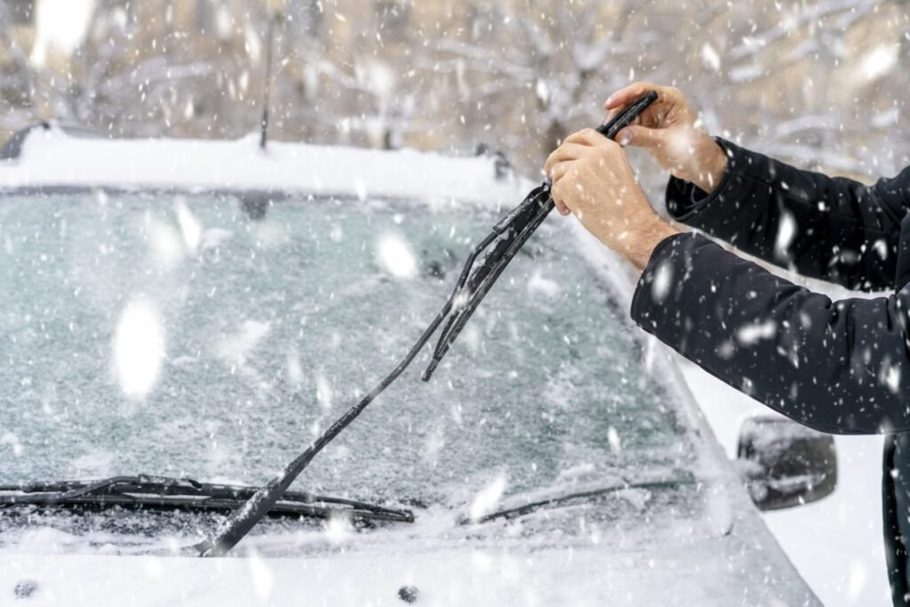 Person clearing snow from windshield